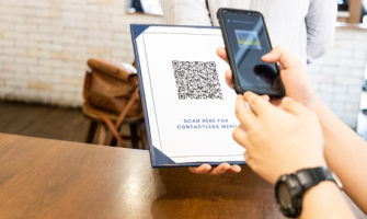 Person scanning contactless menu QR code with smartphone