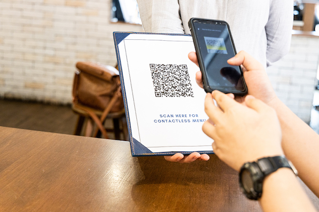 Person scanning contactless menu QR code with smartphone
