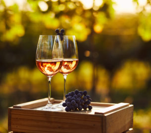 Two glasses of rose wine on a wooden crate in the vineyard